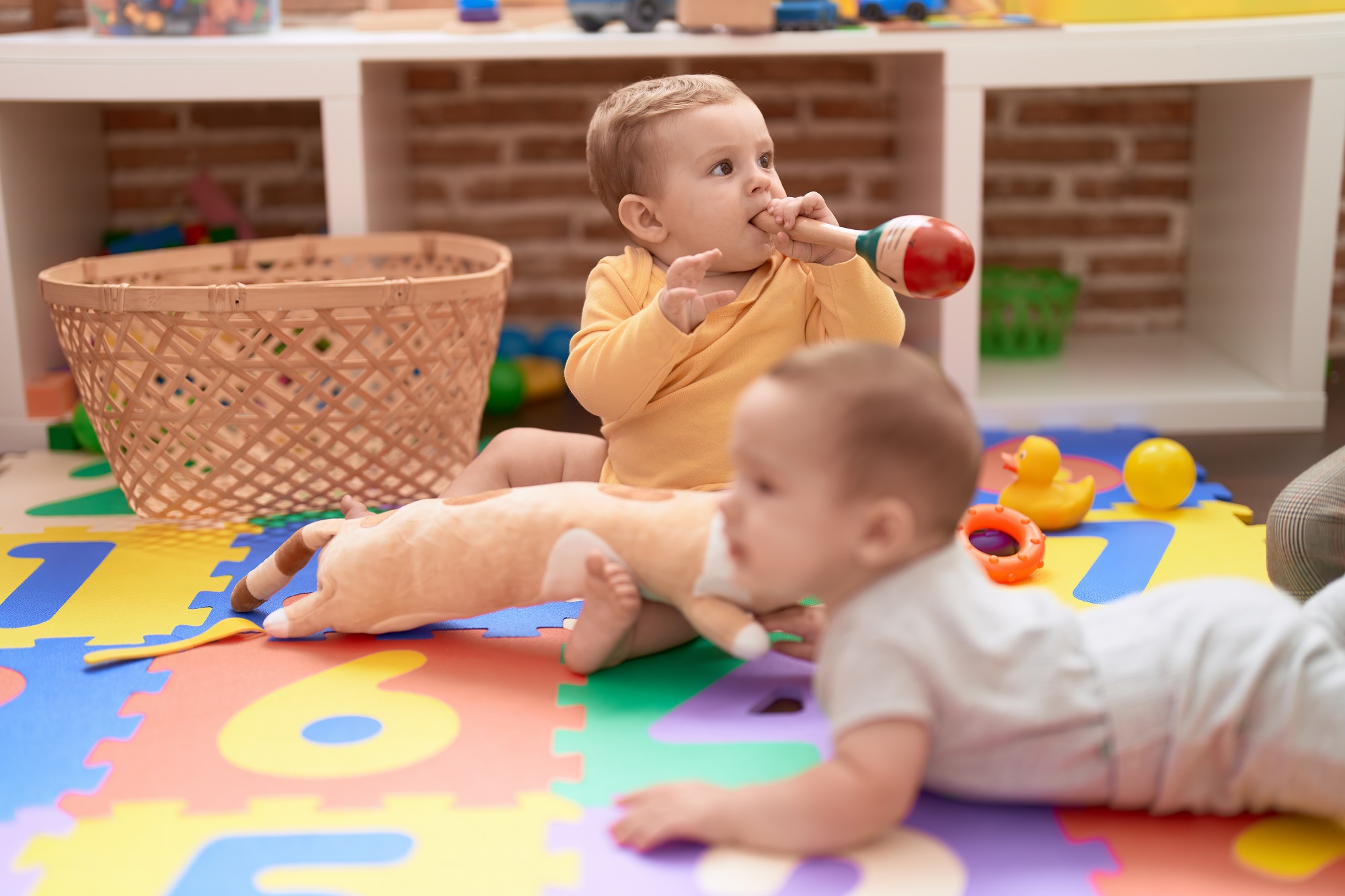 two-toddlers-sucking-maraca-sitting-floor-kindergarten