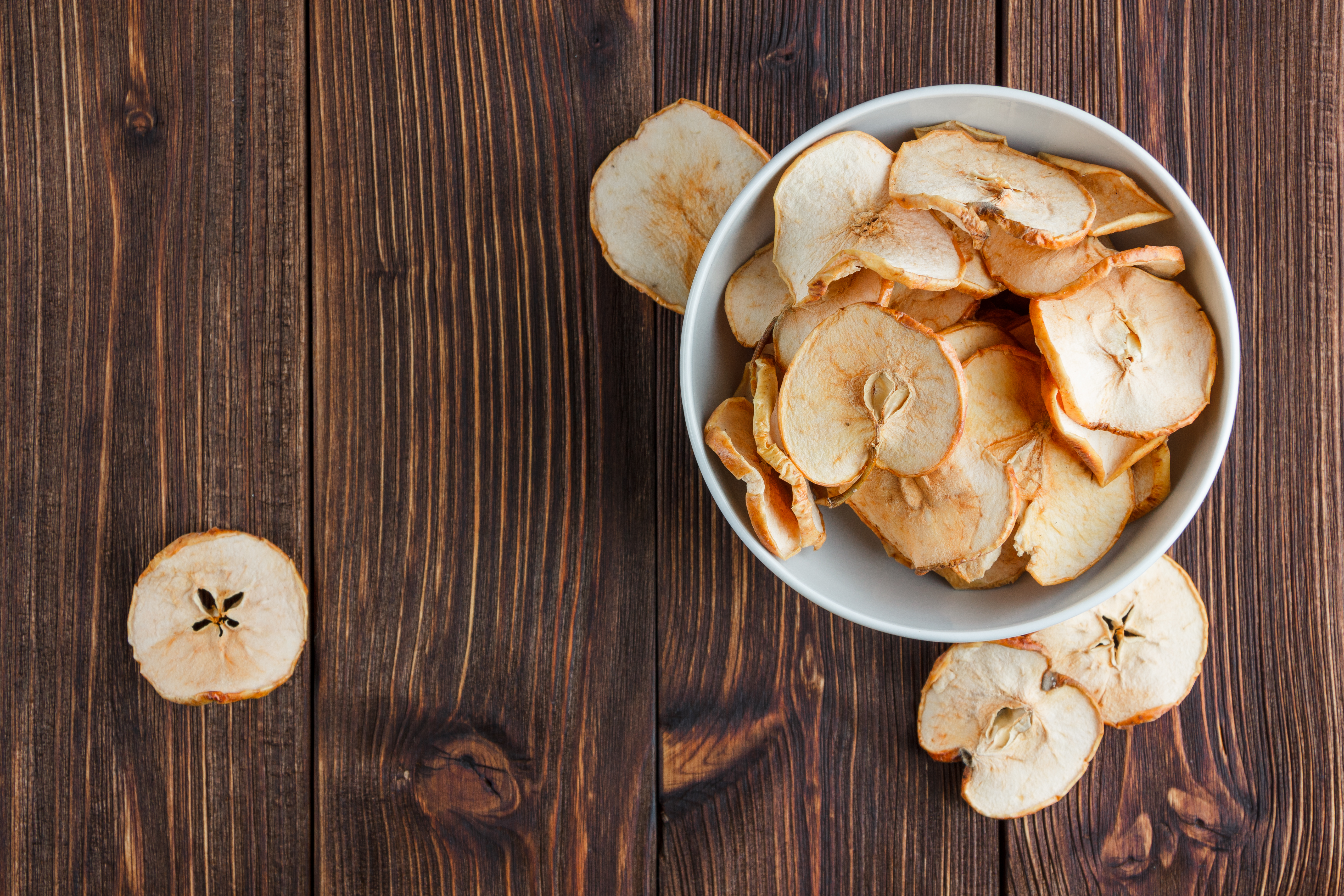 dry-apple-bowl-wooden-background-top-view-space-text